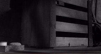 Movie still from “The Incredible Shrinking Man” (1957), directed by Jack Arnold – A person walking in front of a tall building; Extreme Wide shot, Low angle