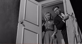Movie still from “The Incredible Shrinking Man” (1957), directed by Jack Arnold – A man and a woman standing in front of an open door; Medium shot, Low angle