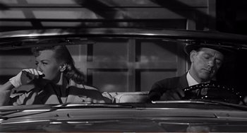 Movie still from “The Incredible Shrinking Man” (1957), directed by Jack Arnold – A man and a woman sitting in the back seat of a car; Medium shot, Low angle