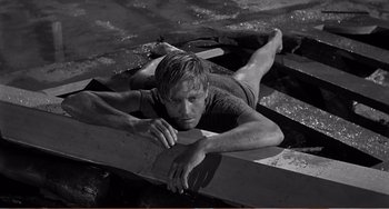 Movie still from “The Incredible Shrinking Man” (1957), directed by Jack Arnold – A man laying on a board in the water; Medium shot, High angle
