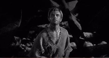 Movie still from “The Incredible Shrinking Man” (1957), directed by Jack Arnold – Black and white photograph of a man wearing a sweater; Medium shot, Low angle