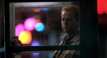 A man standing in front of a window with lights in the background