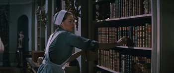 Movie still from “The Inn of the Sixth Happiness” (1958), directed by Mark Robson – A woman is reaching for a book in a library; Medium shot, Low angle
