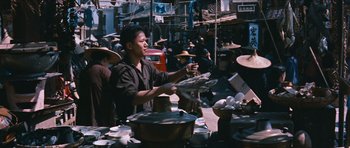 Movie still from “The Inn of the Sixth Happiness” (1958), directed by Mark Robson – A man standing in front of bowls of food on a table; Medium shot, High angle
