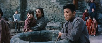 Movie still from “The Inn of the Sixth Happiness” (1958), directed by Mark Robson – A man and a woman and a little girl sitting on steps; Medium shot, Low angle