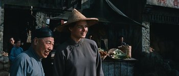 Movie still from “The Inn of the Sixth Happiness” (1958), directed by Mark Robson – A woman wearing a straw hat standing in front of vegetables; Medium shot, Over the shoulder angle