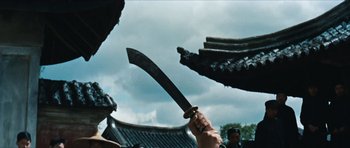 Movie still from “The Inn of the Sixth Happiness” (1958), directed by Mark Robson – A person holding a sword up in the air in front of a building; Close Up shot, Low angle