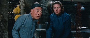 Movie still from “The Inn of the Sixth Happiness” (1958), directed by Mark Robson – A man and a woman standing next to each other in front of an oven; Medium shot, Low angle