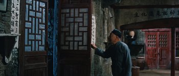 Movie still from “The Inn of the Sixth Happiness” (1958), directed by Mark Robson – A man in a hat is looking at a door; Medium shot, Over the shoulder angle