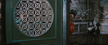 Movie still from “The Inn of the Sixth Happiness” (1958), directed by Mark Robson – A woman in a red dress standing in front of a green door; Medium shot, Over the shoulder angle
