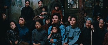 Movie still from “The Inn of the Sixth Happiness” (1958), directed by Mark Robson – A group of people sitting and standing around each other; Wide shot, High angle