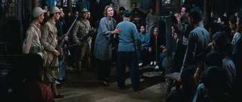 Movie still from “The Inn of the Sixth Happiness” (1958), directed by Mark Robson – An older woman talking to an older man in front of a group of people; Wide shot, Over the shoulder angle