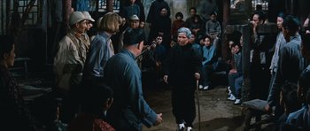 Movie still from “The Inn of the Sixth Happiness” (1958), directed by Mark Robson – An old man is holding a cane in front of a crowd; Wide shot, High angle
