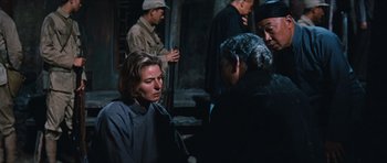 Movie still from “The Inn of the Sixth Happiness” (1958), directed by Mark Robson – A group of people standing next to each other on the street; Medium shot, Over the shoulder angle