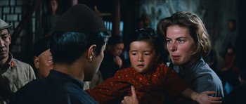 Movie still from “The Inn of the Sixth Happiness” (1958), directed by Mark Robson – A man holding a baby in a crowd of people; Close Up shot, Over the shoulder angle