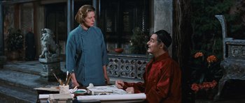 Movie still from “The Inn of the Sixth Happiness” (1958), directed by Mark Robson – A man and a woman sitting at a table with papers; Medium shot, Over the shoulder angle