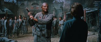 Movie still from “The Inn of the Sixth Happiness” (1958), directed by Mark Robson – A man holding a sword in a crowded area; Medium shot, Over the shoulder angle