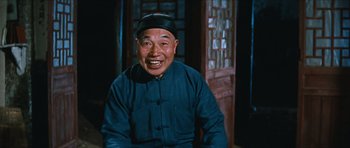 Movie still from “The Inn of the Sixth Happiness” (1958), directed by Mark Robson – An older man wearing a blue shirt and a black hat; Medium shot, Low angle