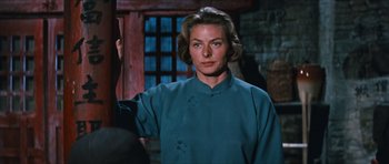 Movie still from “The Inn of the Sixth Happiness” (1958), directed by Mark Robson – A woman wearing a blue shirt standing in front of a brick wall; Medium shot, Over the shoulder angle