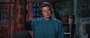 Movie still from “The Inn of the Sixth Happiness” (1958), directed by Mark Robson – A woman in a blue shirt standing next to a wooden door; Close Up shot, Over the shoulder angle