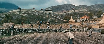 Movie still from “The Inn of the Sixth Happiness” (1958), directed by Mark Robson – A group of people in a field near a wall; Extreme Wide shot, High angle