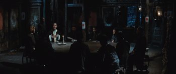 Movie still from “The Inn of the Sixth Happiness” (1958), directed by Mark Robson – A group of people sitting at a table in a dark room; Wide shot, Over the shoulder angle