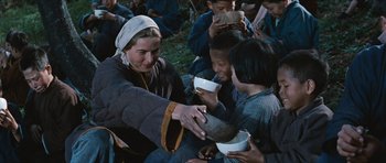 Movie still from “The Inn of the Sixth Happiness” (1958), directed by Mark Robson – A group of people sitting on the ground eating food; Medium shot, Low angle