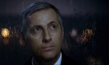 Movie still from “The Grilling” (1981), directed by Claude Miller – A person wearing a suit and tie; Close Up shot, Low angle