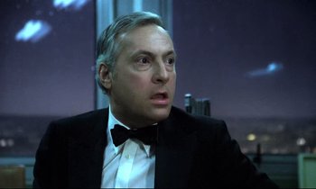 Movie still from “The Grilling” (1981), directed by Claude Miller – A person wearing a suit and a bow tie; Close Up shot, Low angle