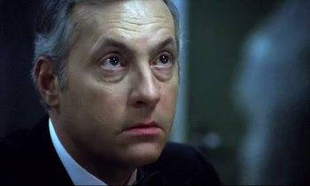 Movie still from “The Grilling” (1981), directed by Claude Miller – An older man in a suit and tie looking to his left; Close Up shot, High angle