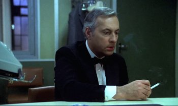Movie still from “The Grilling” (1981), directed by Claude Miller – A man sitting at a table in front of a mirror; Close Up shot, Over the shoulder angle