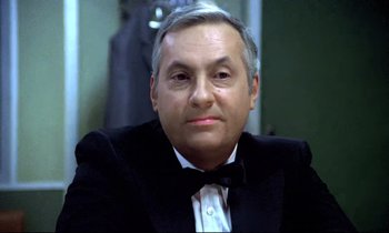 Movie still from “The Grilling” (1981), directed by Claude Miller – An older man in a tuxedo sitting in front of a mirror; Close Up shot, Low angle