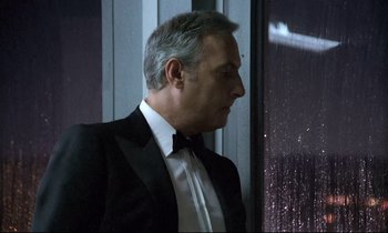 Movie still from “The Grilling” (1981), directed by Claude Miller – A person wearing a suit near a window; Close Up shot, Low angle