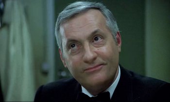 Movie still from “The Grilling” (1981), directed by Claude Miller – A person wearing a suit and tie; Close Up shot, Low angle