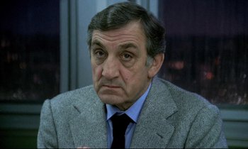 Movie still from “The Grilling” (1981), directed by Claude Miller – An older man wearing a suit and tie; Close Up shot, High angle