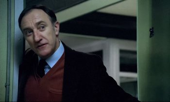 Movie still from “The Grilling” (1981), directed by Claude Miller – A person wearing a suit and tie; Close Up shot, Low angle