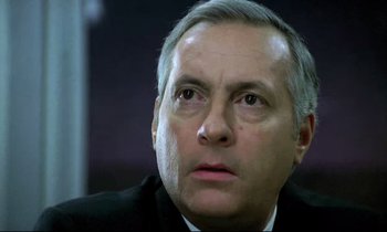Movie still from “The Grilling” (1981), directed by Claude Miller – A man in a suit and tie looking to his left; Close Up shot, Low angle