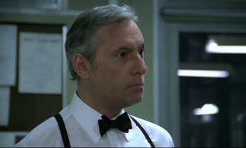 Movie still from “The Grilling” (1981), directed by Claude Miller – A person wearing a bow tie; Close Up shot, Low angle