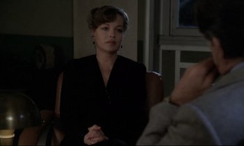 Movie still from “The Grilling” (1981), directed by Claude Miller – A woman sitting in front of a man in a room; Medium shot, Over the shoulder angle