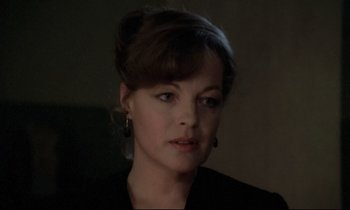 Movie still from “The Grilling” (1981), directed by Claude Miller – A person wearing a suit and tie; Close Up shot, Over the shoulder angle