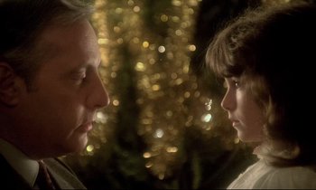 Movie still from “The Grilling” (1981), directed by Claude Miller – A man and a girl face to face in front of a christmas tree; Close Up shot, Over the shoulder angle