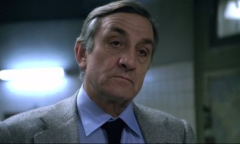 Movie still from “The Grilling” (1981), directed by Claude Miller – An older man wearing a suit and tie; Close Up shot, Low angle