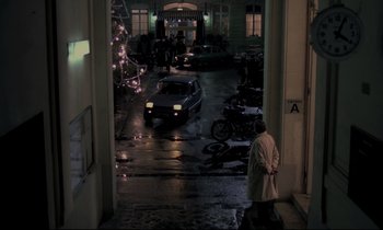 Movie still from “The Grilling” (1981), directed by Claude Miller – A man standing in a parking lot next to parked cars; Extreme Wide shot, High angle