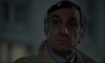 Movie still from “The Grilling” (1981), directed by Claude Miller – An older man wearing a jacket and a tie; Close Up shot, Over the shoulder angle
