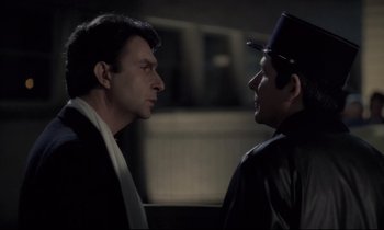 Movie still from “The Grilling” (1981), directed by Claude Miller – Two men are facing each other in the dark; Close Up shot, Over the shoulder angle