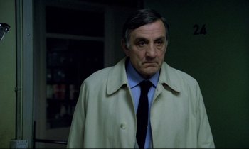 Movie still from “The Grilling” (1981), directed by Claude Miller – An older man wearing a jacket and a tie; Close Up shot, Over the shoulder angle