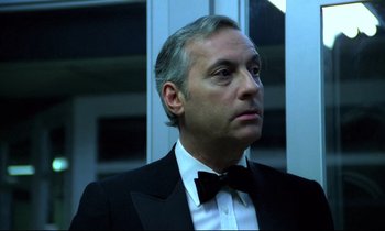 Movie still from “The Grilling” (1981), directed by Claude Miller – A person wearing a suit and bow tie; Close Up shot, Low angle