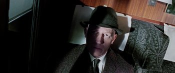 Movie still from “The Ipcress File” (1965), directed by Sidney J. Furie – A man wearing a suit and a hat; Close Up shot, Overhead angle