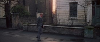 Movie still from “The Ipcress File” (1965), directed by Sidney J. Furie – A man walking down the street in front of a building; Wide shot, Low angle