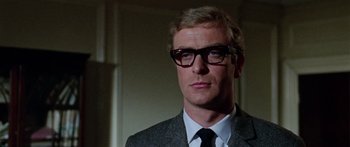Movie still from “The Ipcress File” (1965), directed by Sidney J. Furie – A person wearing glasses and a suit; Close Up shot, Low angle